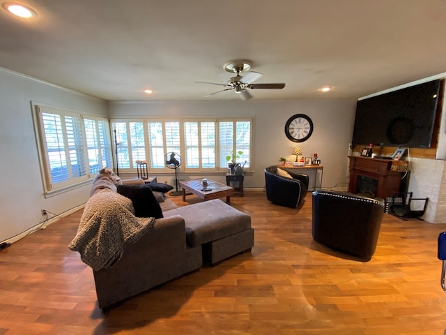 living room featuring ceiling fan, a fireplace, and light hardwood / wood-style floors