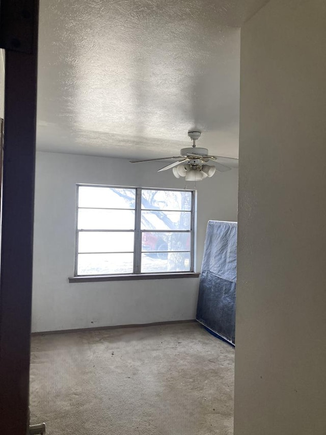 spare room with ceiling fan, light colored carpet, and a textured ceiling