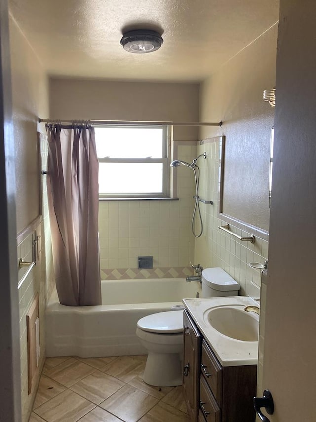 full bathroom featuring tile walls, vanity, a textured ceiling, toilet, and shower / bath combo with shower curtain