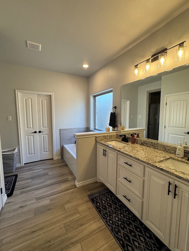 bathroom featuring hardwood / wood-style flooring, vanity, and a washtub