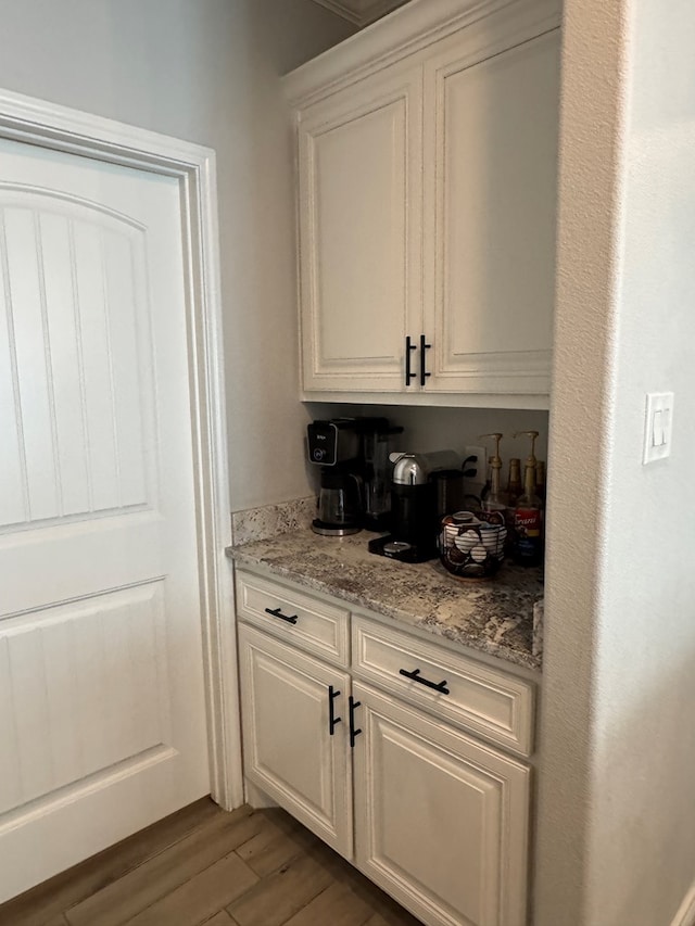 bar featuring white cabinetry, light stone countertops, and dark hardwood / wood-style floors