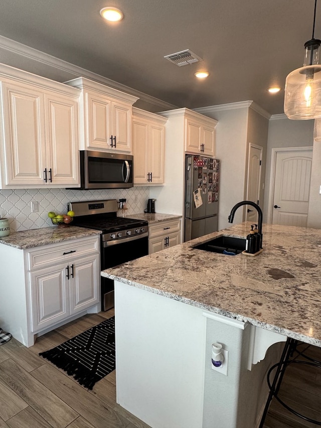 kitchen featuring pendant lighting, sink, white cabinets, light stone counters, and stainless steel appliances