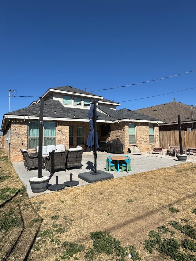 rear view of property with an outdoor living space, a patio, and a lawn