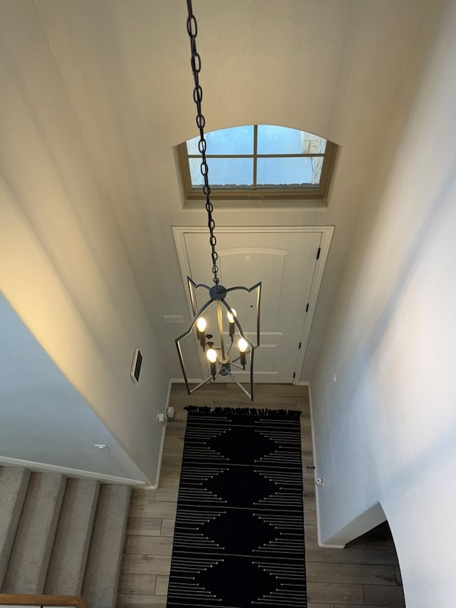 stairs with an inviting chandelier and hardwood / wood-style flooring