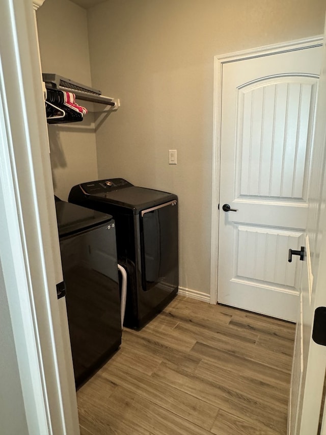 laundry room with washing machine and clothes dryer and light wood-type flooring