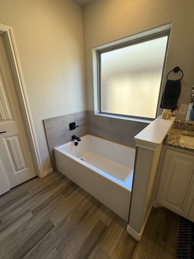 bathroom featuring hardwood / wood-style flooring, vanity, and a bath