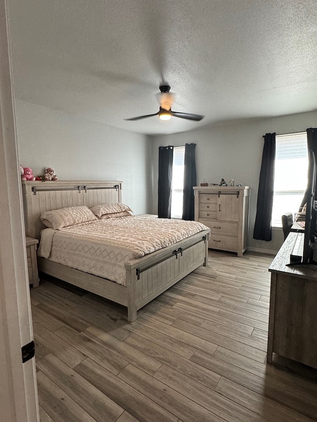 bedroom with multiple windows, ceiling fan, a textured ceiling, and light wood-type flooring