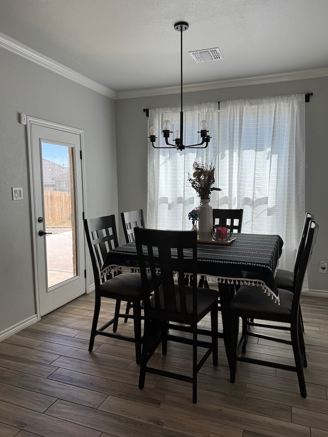 dining area featuring ornamental molding, a chandelier, and hardwood / wood-style floors