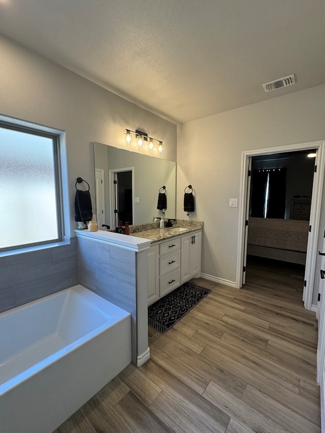 bathroom featuring vanity, a tub, hardwood / wood-style floors, and a textured ceiling