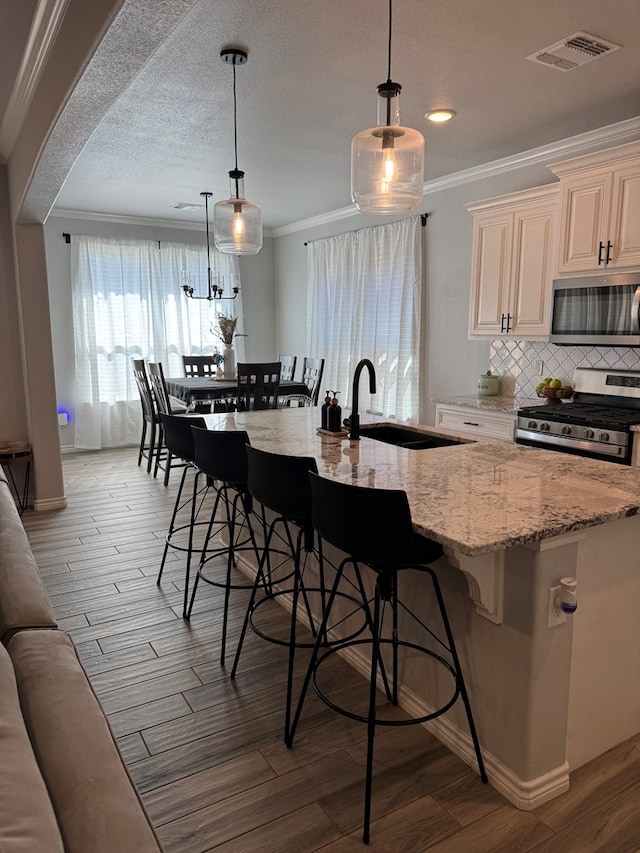 kitchen with crown molding, appliances with stainless steel finishes, and decorative light fixtures