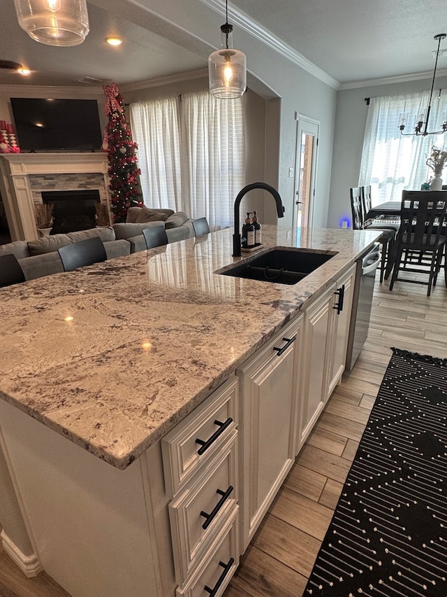 kitchen featuring a kitchen island with sink, decorative light fixtures, dishwasher, and sink