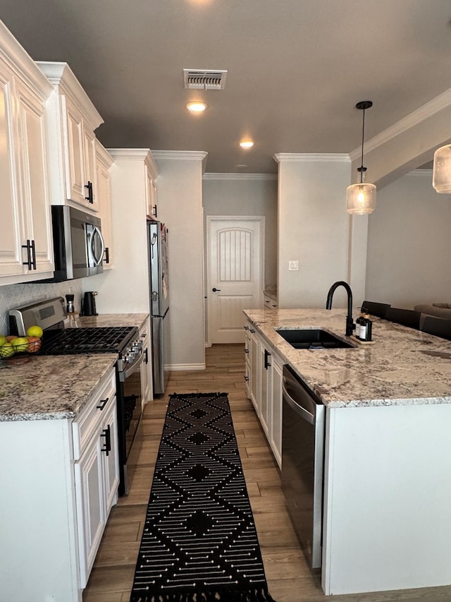 kitchen with sink, white cabinetry, stainless steel appliances, light stone counters, and decorative light fixtures