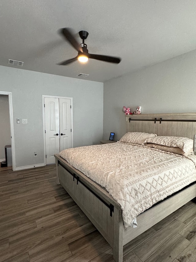 bedroom with ceiling fan, dark wood-type flooring, a textured ceiling, and a closet