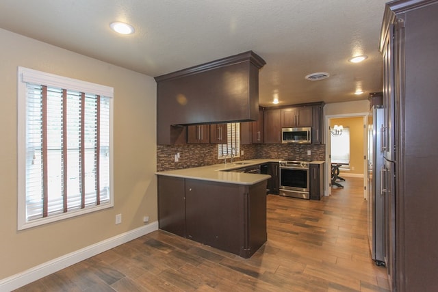 kitchen featuring kitchen peninsula, dark hardwood / wood-style flooring, a textured ceiling, stainless steel appliances, and sink