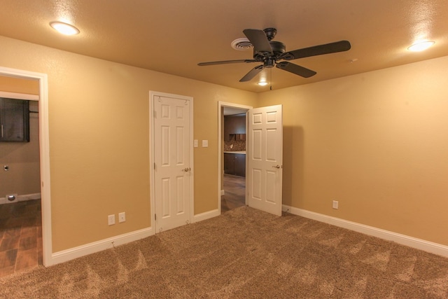 unfurnished bedroom featuring dark colored carpet, a textured ceiling, and ceiling fan