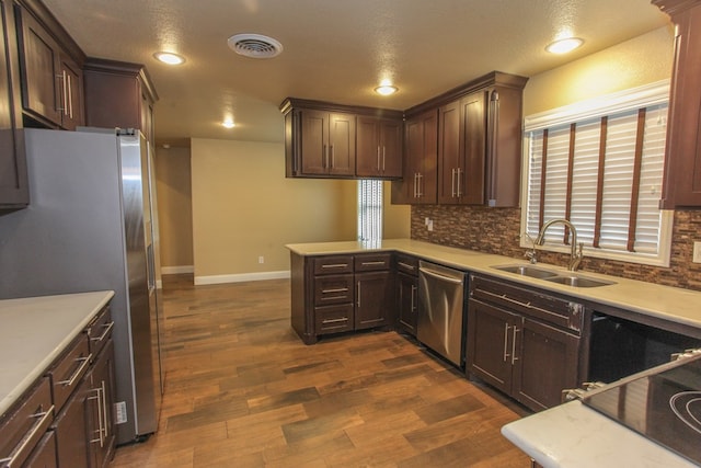 kitchen featuring sink, dark hardwood / wood-style floors, backsplash, a textured ceiling, and appliances with stainless steel finishes