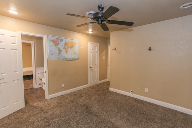 unfurnished room with dark colored carpet and ceiling fan