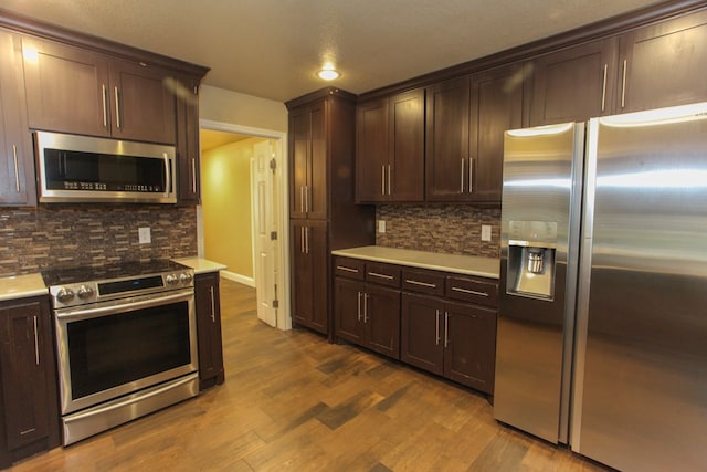 kitchen with hardwood / wood-style flooring, backsplash, dark brown cabinetry, and stainless steel appliances