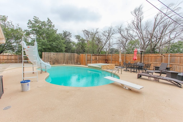 view of pool featuring a diving board, a patio area, a water slide, and an outdoor hot tub