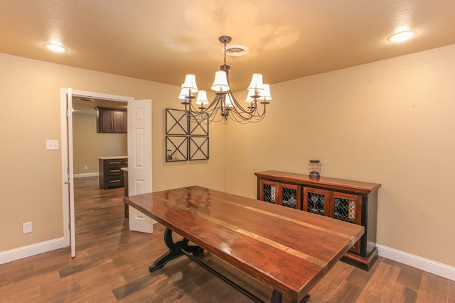 dining area with dark hardwood / wood-style floors and a notable chandelier