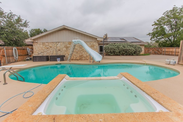 view of swimming pool featuring an in ground hot tub, a patio, and a water slide