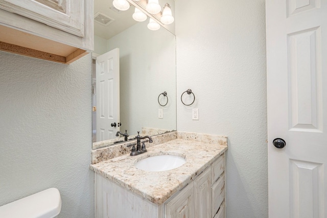 bathroom featuring vanity, a chandelier, and toilet