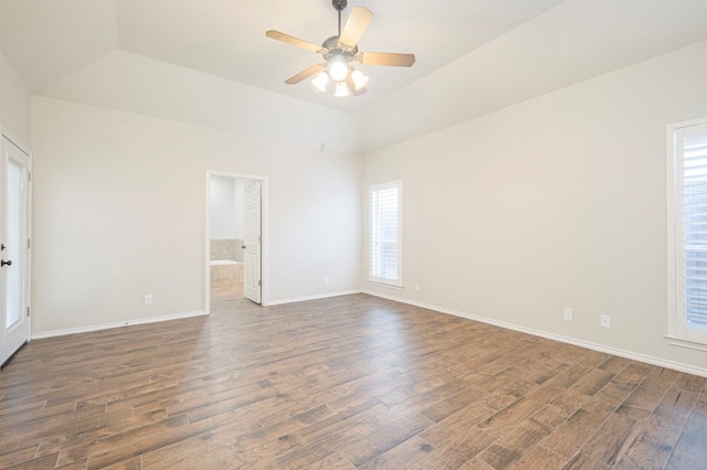 empty room with dark hardwood / wood-style flooring, a raised ceiling, and ceiling fan