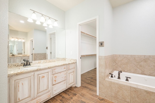 bathroom with vanity, hardwood / wood-style floors, and tiled bath