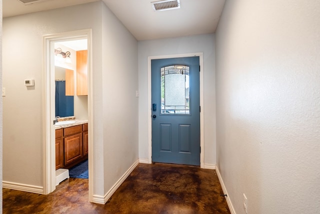 doorway to outside featuring visible vents, a sink, finished concrete flooring, and baseboards