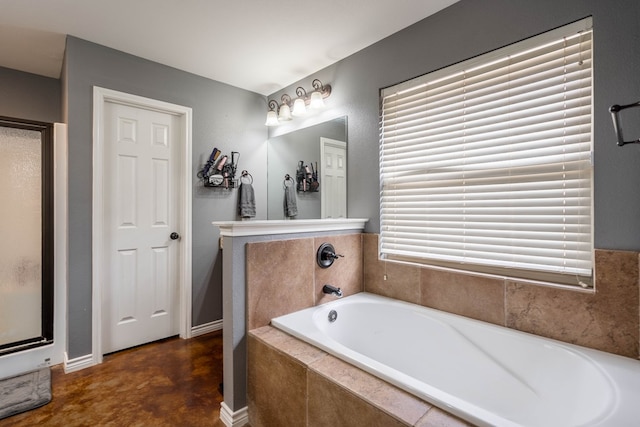 bathroom featuring finished concrete flooring, baseboards, a stall shower, and a garden tub