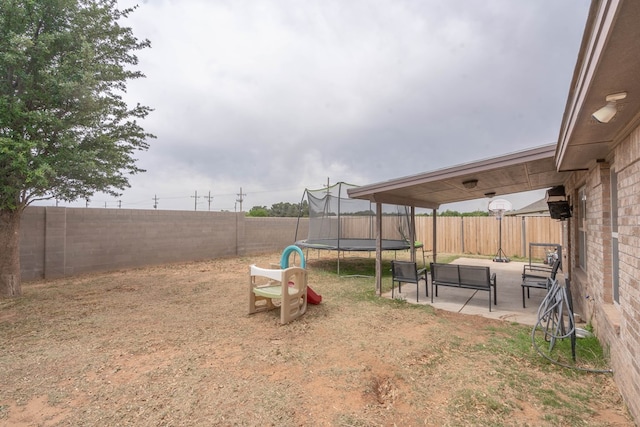 view of yard featuring a patio, a fenced backyard, and a trampoline