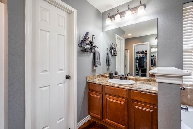 bathroom with vanity, a textured wall, and a walk in closet
