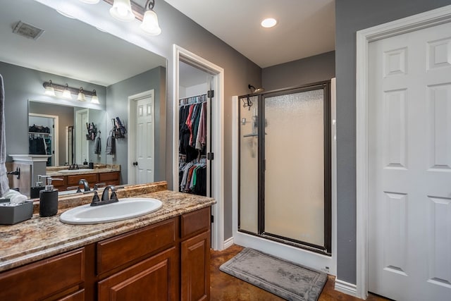 full bath with vanity, a spacious closet, a stall shower, and visible vents