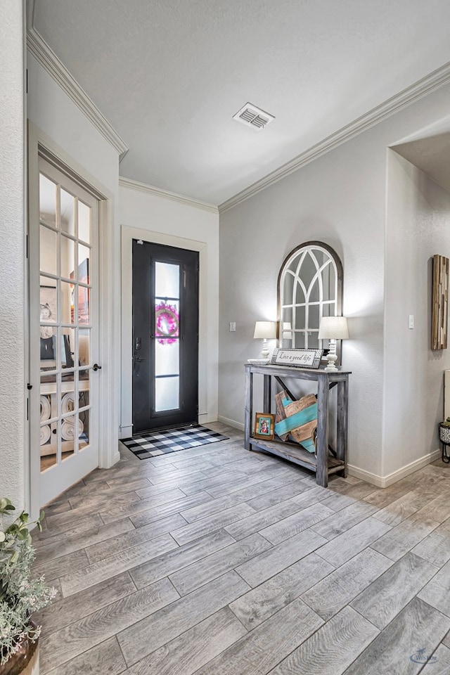 entrance foyer featuring wood tiled floor, visible vents, crown molding, and baseboards