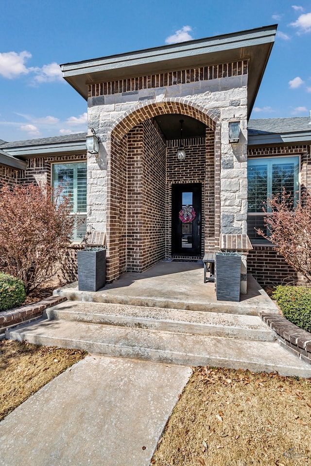 view of exterior entry with stone siding and brick siding