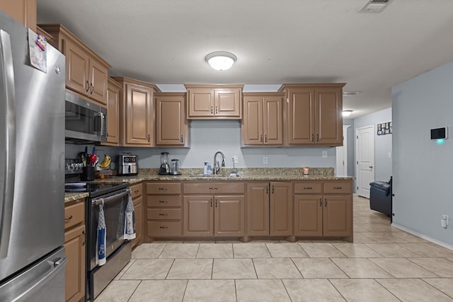 1004 Jefferson St, Odessa, TX 79761 - kitchen with stainless steel appliances, a sink, light tile patterned flooring, light stone countertops, and baseboards
