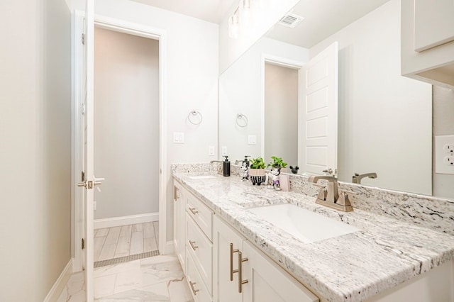 full bath with visible vents, marble finish floor, double vanity, and a sink