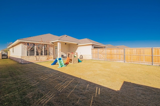 rear view of property with a lawn, stucco siding, and a fenced backyard