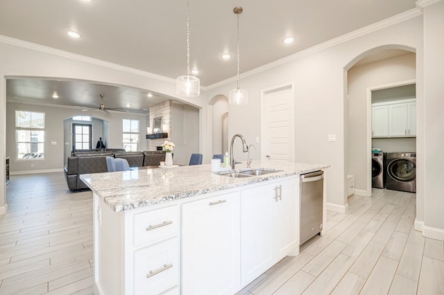 kitchen with washer and clothes dryer, dishwasher, arched walkways, and a sink