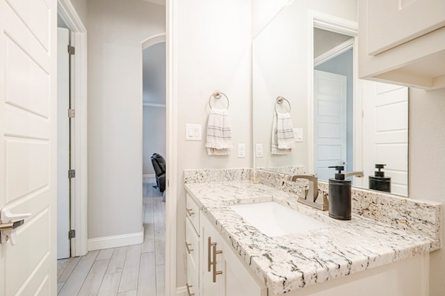 bathroom featuring baseboards, wood finish floors, and vanity