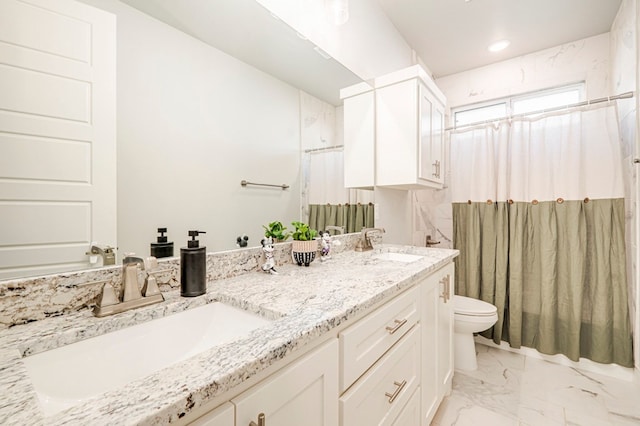 full bathroom featuring toilet, marble finish floor, a sink, and double vanity
