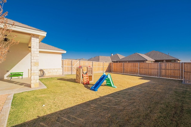 view of yard featuring a playground, a fenced backyard, and a patio area