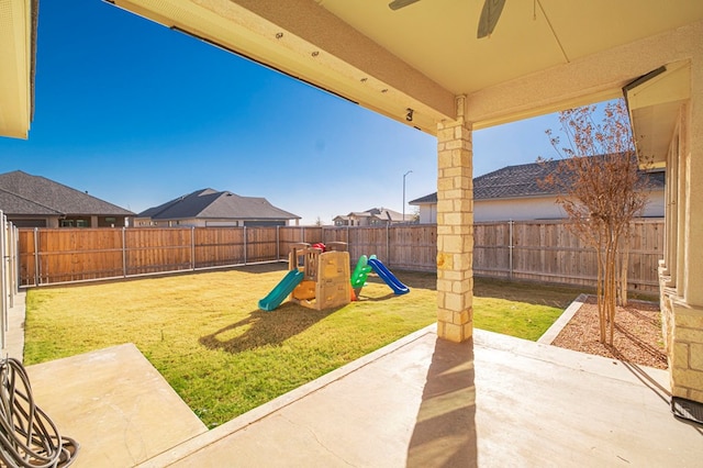 view of yard featuring ceiling fan, a playground, a fenced backyard, and a patio area