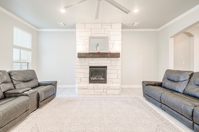 living area featuring a fireplace, a ceiling fan, baseboards, ornamental molding, and wood finished floors