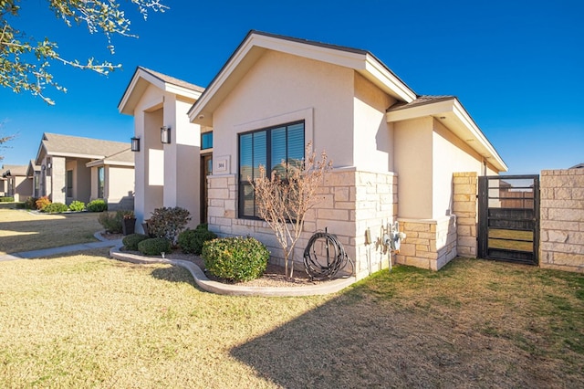 view of property exterior with stucco siding, a gate, a lawn, and stone siding