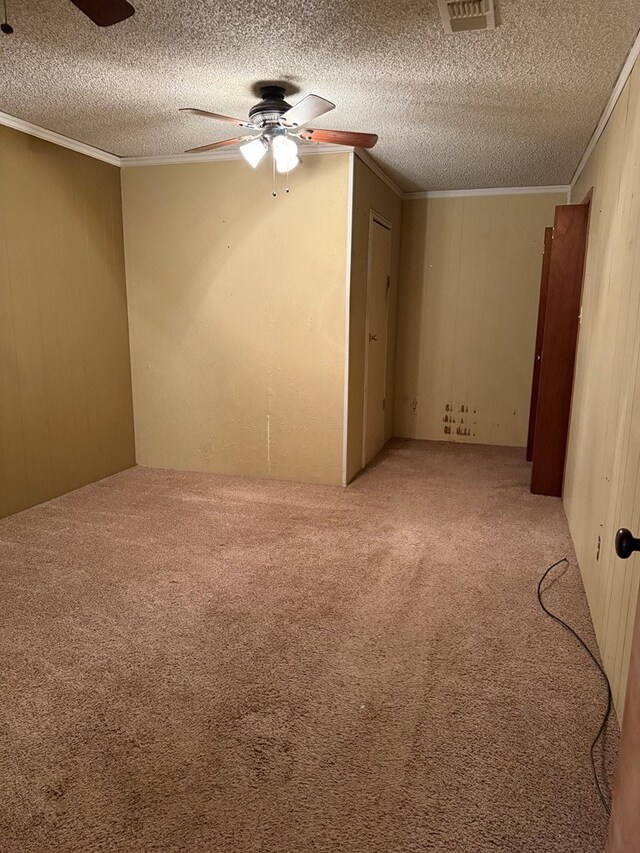 2203 40th St, Snyder, TX 79549 - spare room featuring ceiling fan, light carpet, crown molding, a textured ceiling, and wood walls
