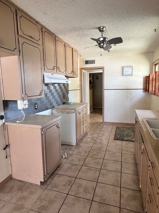 2203 40th St, Snyder, TX 79549 - kitchen with under cabinet range hood, a ceiling fan, tasteful backsplash, light tile patterned flooring, and a textured ceiling