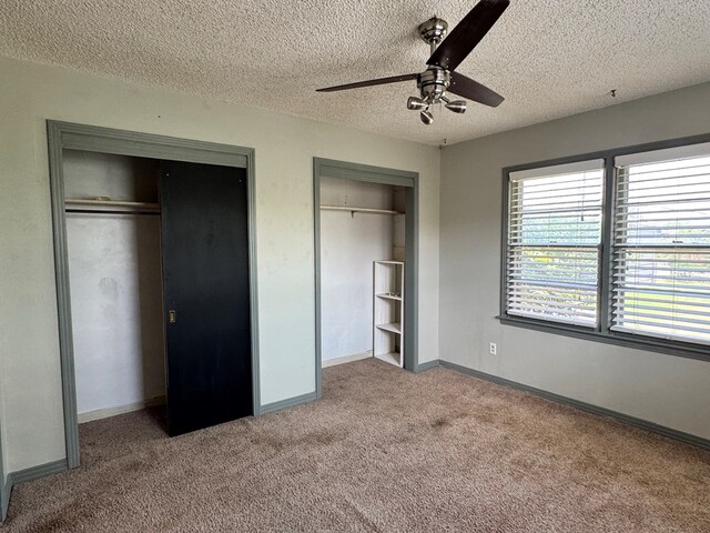 2203 40th St, Snyder, TX 79549 - unfurnished bedroom featuring light colored carpet, multiple closets, a textured ceiling, baseboards, and a ceiling fan