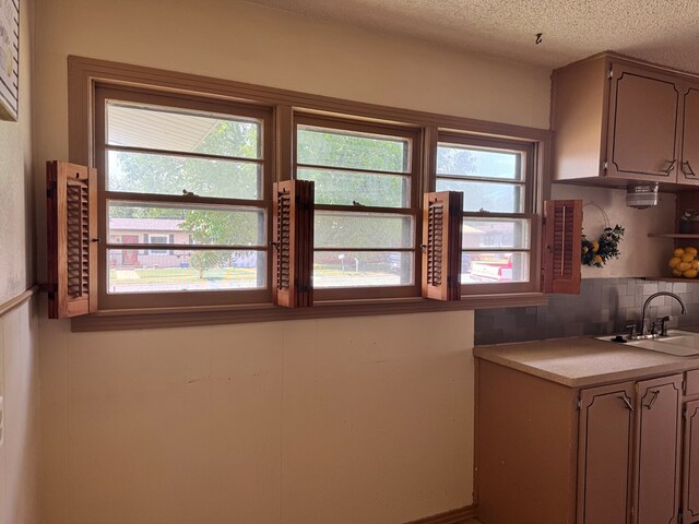 2203 40th St, Snyder, TX 79549 - kitchen with a sink, light countertops, backsplash, plenty of natural light, and a textured ceiling