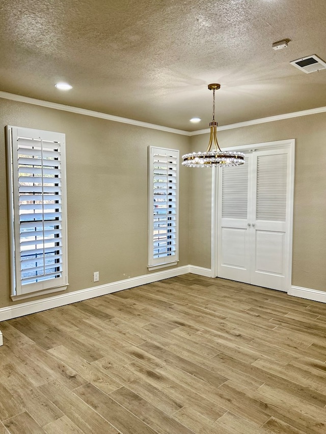 unfurnished dining area featuring crown molding, a notable chandelier, a textured ceiling, and hardwood / wood-style flooring